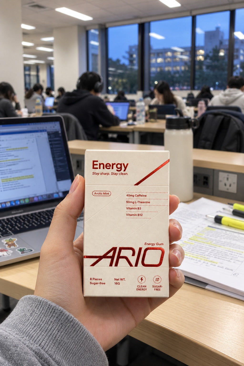 A hand holding the ARIO pack in a busy university study room